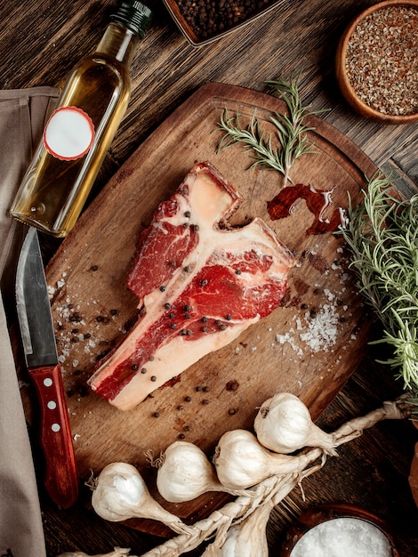 Ein Stück Fleisch für Steak auf einem Holzbrett mit Gewürzen bestreut