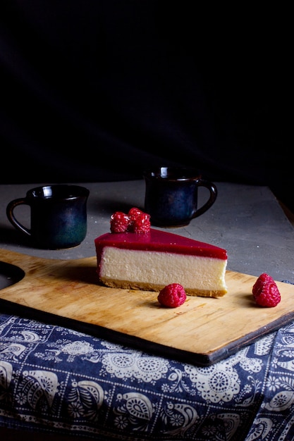 Kostenloses Foto ein stück himbeerkäsekuchen auf holzschneidebrett gelegt