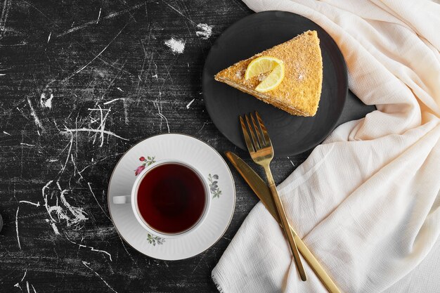 Ein Stück Honigkuchen mit Zitrone mit einer Tasse Tee.