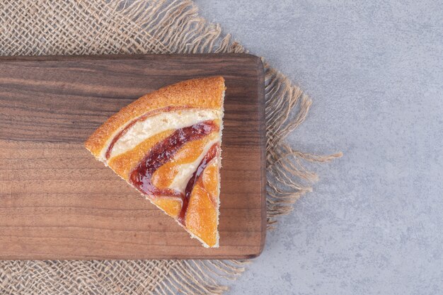 Ein Stück Kuchen auf einem Holzbrett auf Marmortisch.