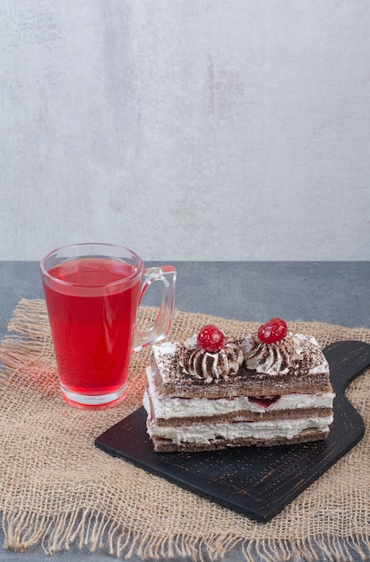 Ein Stück Kuchen mit einer Tasse frischem Saft auf Sackleinen. .