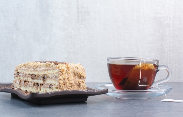 Kostenloses Foto ein stück kuchen mit tasse aromakaffee auf grauem tisch.