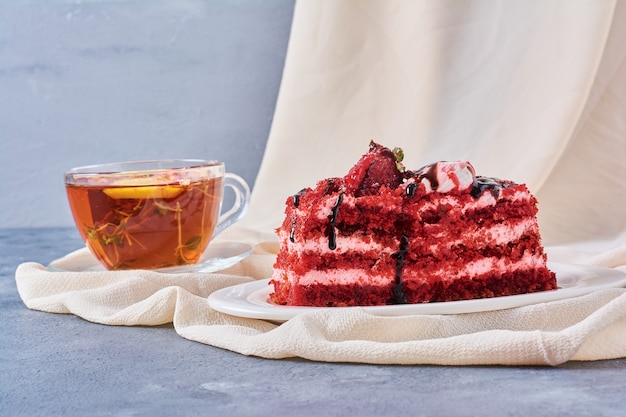 Ein Stück roter Samtkuchen in einem weißen Teller mit Tee.