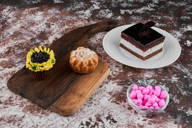 Ein Stück Schokoladenkäsekuchen in einem weißen Teller mit Cupcakes.