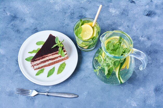 Ein Stück Schokoladenkuchen in einem weißen Teller mit Mojito-Cocktail.