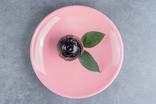 Kostenloses Foto ein stück schokoladenkuchen mit blättern auf einem rosa teller