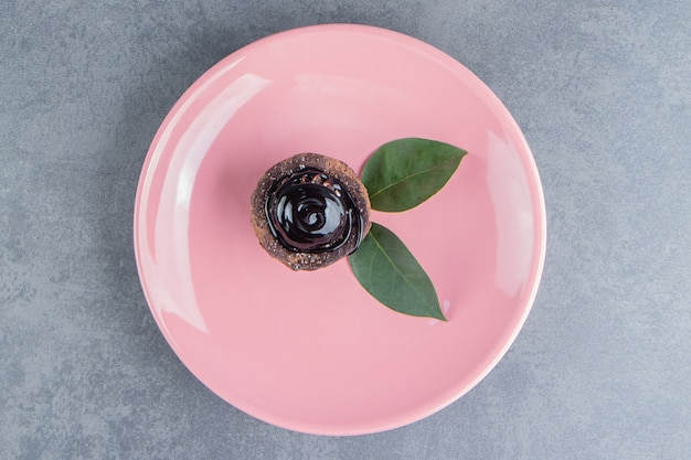 Ein Stück Schokoladenkuchen mit Blättern auf einem rosa Teller