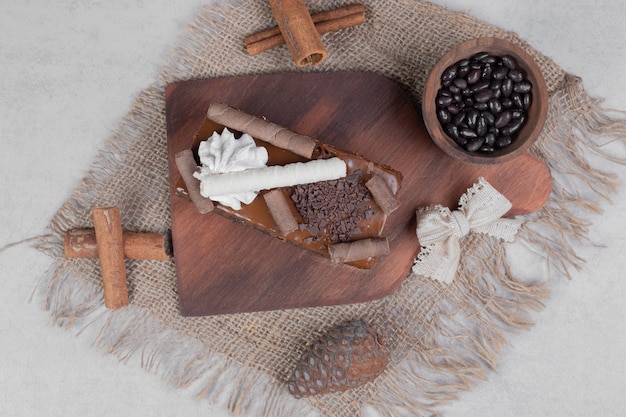 Ein Stück Schokoladenkuchen, Zimt und Tannenzapfen auf Sackleinen. Hochwertiges Foto