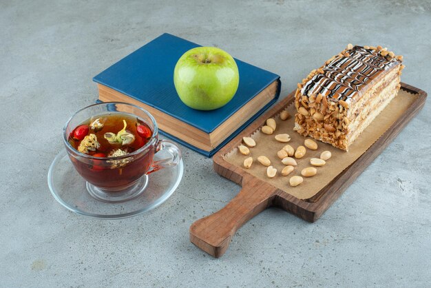 Ein Stück süßer Kuchen mit schwarzem Tee und Apfel.