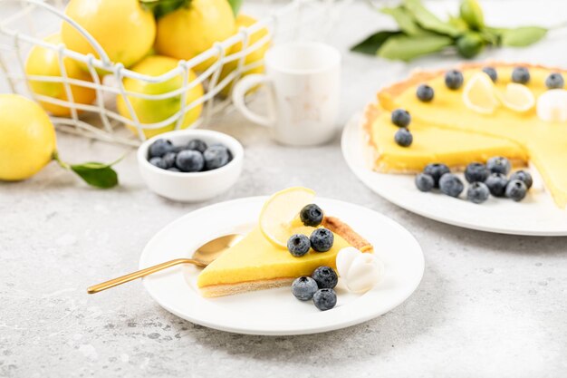 Ein Stück Zitronenkuchen mit Heidelbeeren auf einem weißen Teller