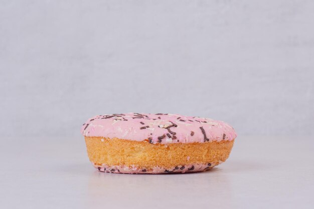 Ein süßer rosa Donut auf weißem Tisch.
