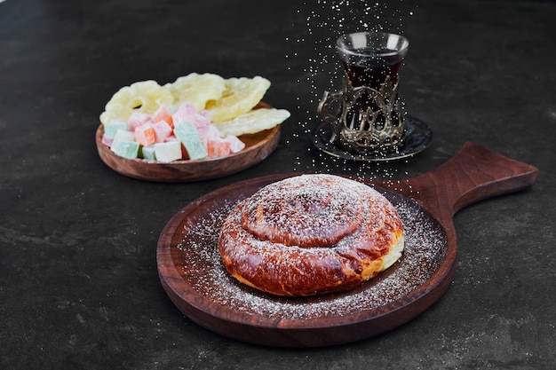 Kostenloses Foto ein süßes brötchen mit trockenen früchten und einem glas tee. hochwertiges foto