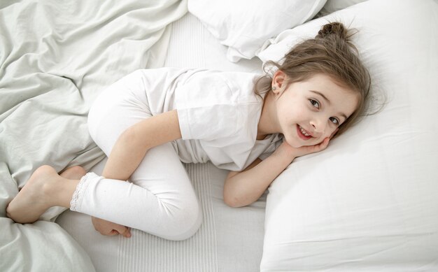 Ein süßes kleines Mädchen schläft in einem weißen Bett. Konzept der kindlichen Entwicklung und des Schlafes.