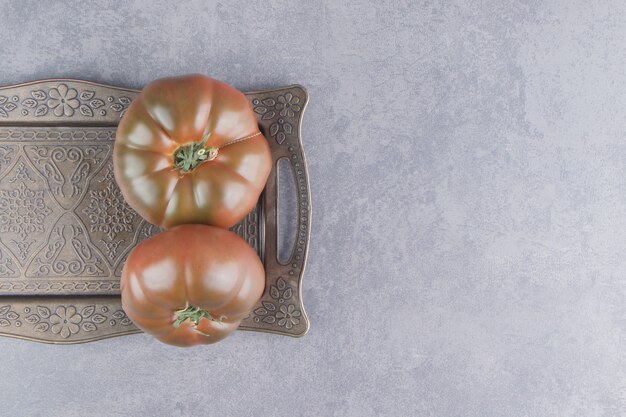 Ein Tablett mit würzigen Tomaten auf der Marmoroberfläche