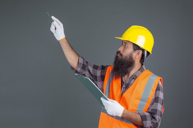 Ein Technikmann, der einen gelben Sturzhelm mit einem Design auf einem Grau trägt.