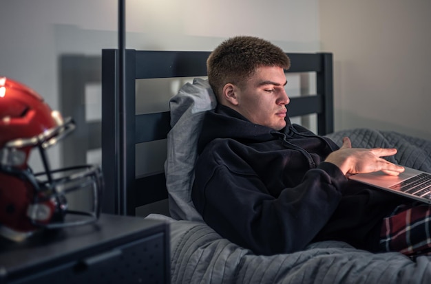 Kostenloses Foto ein teenager sitzt in einem zimmer auf einem bett und benutzt einen laptop