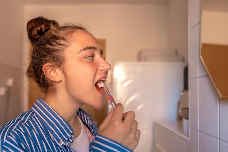 Kostenlose Foto ein teenagermädchen putzt sich die zähne, ein mädchen putzt sich ihre zähne vor dem spiegel im badezimmer.