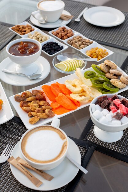 Ein Teetisch mit Vorderansicht und Marmeladenkaffee-Marmeladennüssen, Süßigkeiten, getrockneten Früchten und Süßigkeiten im Restaurant während des Tages-Teetisches süß draußen