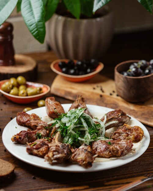 Ein Teller Lamm entrecote Rippen Kebab mit Zwiebeln und Gemüse