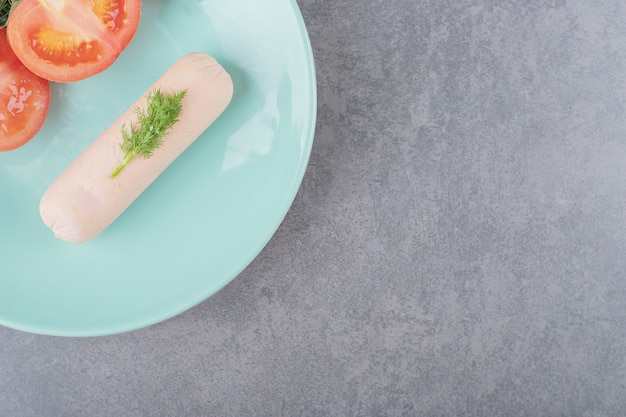 Ein teller mit gekochter wurst und geschnittenen roten tomaten