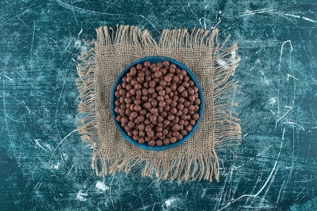 Ein Teller mit Maisbällchen auf einem Sackleinenstoff, auf blauem Hintergrund. Foto in hoher Qualität