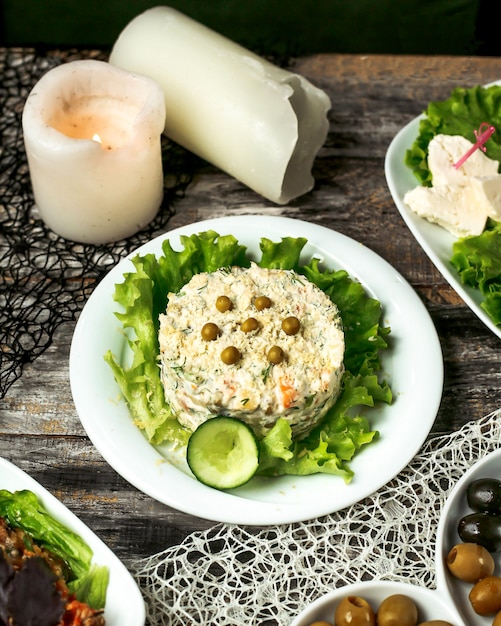 Ein Teller mit Oliviesalat, garniert mit Gurke und Salat