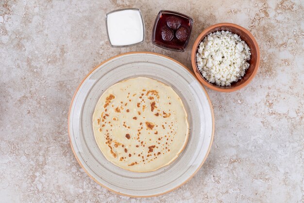 Ein Teller mit Pfannkuchen mit Sauerrahm und Erdbeermarmelade