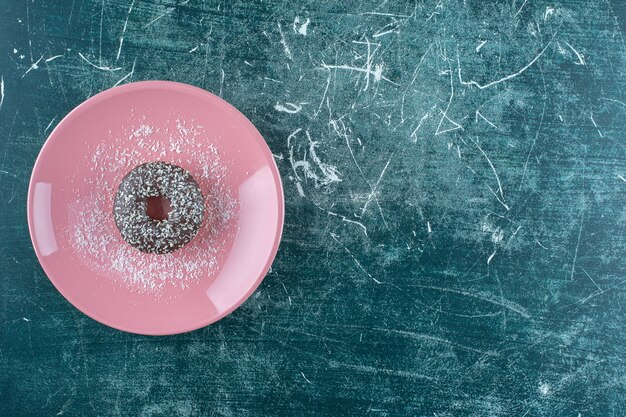 Ein Teller mit Schokoladenkrapfen auf blauem Hintergrund. Foto in hoher Qualität