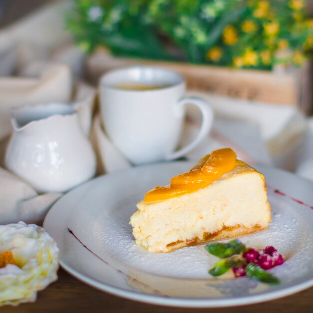 Ein Teller mit Stück Käsekuchen, garniert mit Aprikosenscheiben