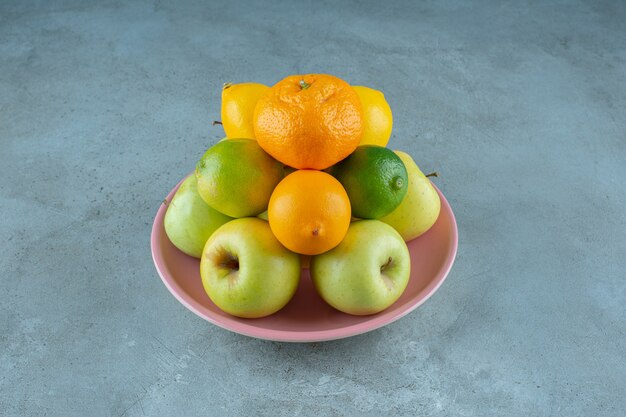 Ein Teller mit verschiedenen Früchten, auf dem Marmorhintergrund. Foto in hoher Qualität