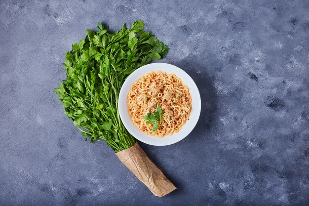 Ein Teller Pasta auf blauem Tisch.