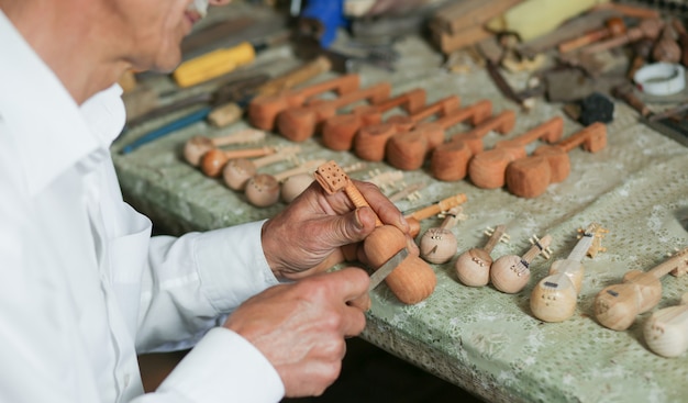 Ein Tischlermeister, der Holz schnitzt und Teerinstrumentenfiguren herstellt