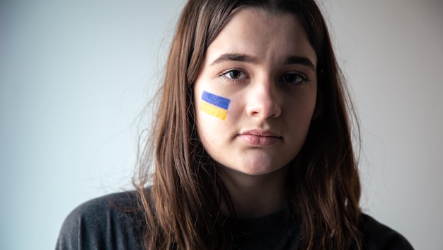 Ein ukrainisches mädchen mit einer gemalten flagge der ukraine auf ihrem gesicht