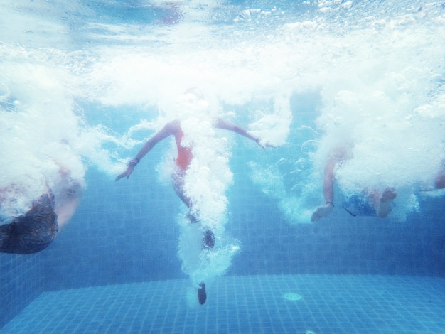 Ein Unterwasserschuß einer Gruppe von Personen, die hinunter in einen Swimmingpool springt
