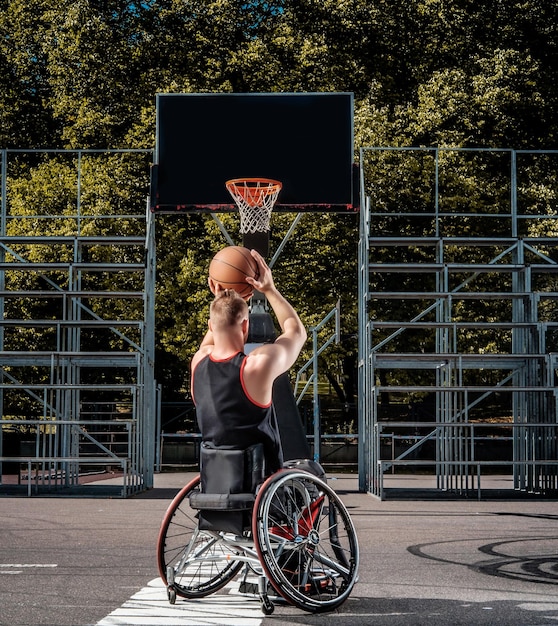 Ein verkrüppelter Basketballspieler im Rollstuhl spielt auf einem offenen Spielfeld.