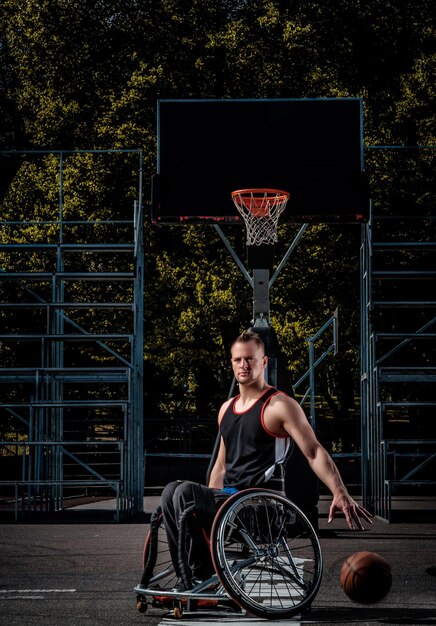 Ein verkrüppelter Basketballspieler im Rollstuhl spielt auf einem offenen Spielfeld.