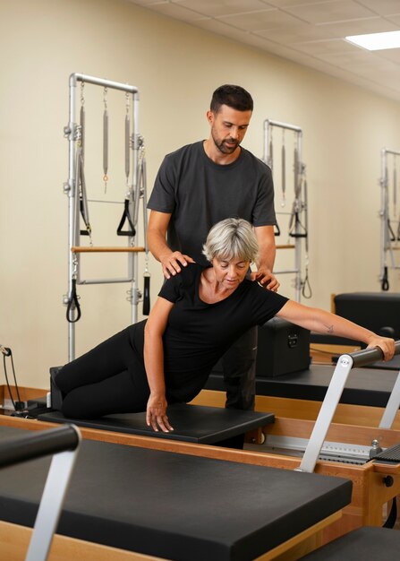 Ein voller Mann hilft einer Frau im Pilates-Unterricht