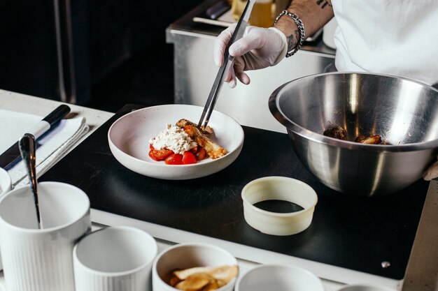 Ein Vorderansicht-Koch, der Mahlzeit im weißen Anzug und in den Handschuhen vorbereitet, die Fleischmehl innerhalb des Küchenlebensmittelmahlzeitfleischs entwerfen