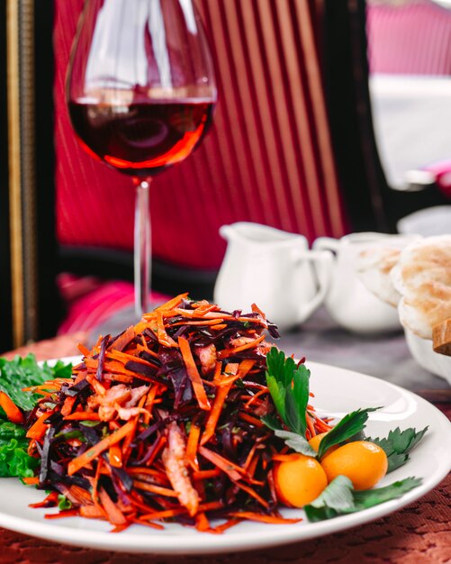 Ein Vorderansichtgemüse, das zusammen mit grünem Salat innerhalb der weißen Platte auf dem Tisch gebraten wird