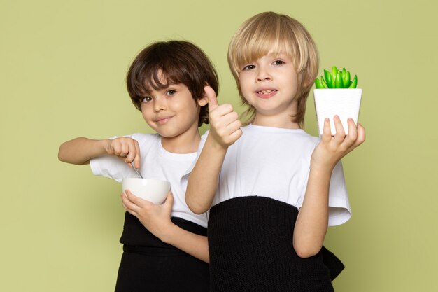 Ein Vorderansichtpaar der Jungen, die lächeln, grüne grüne Pflanze und Kaffee halten