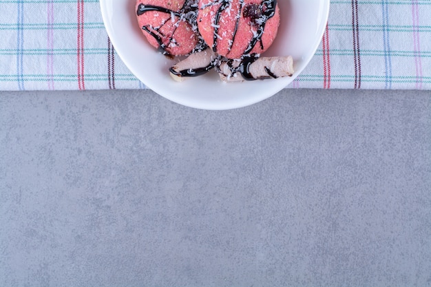 Ein weißer Teller mit leckeren rosa Donuts mit Streuseln und süßen Sticks.