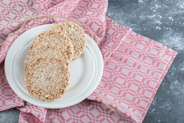 Ein weißer teller voller puffreisbrot auf einer tischdecke.