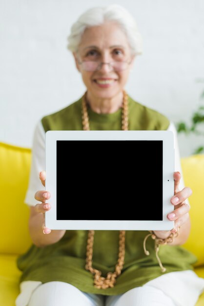 Eine ältere Frau, die digitale Tablette mit leerem Bildschirm zeigt