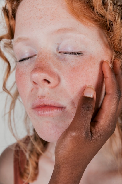 Eine afrikanische junge Frau, welche die Backe ihres kaukasischen Freundes berührt