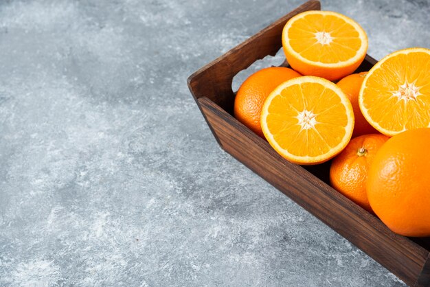 Eine alte Holzkiste voller geschnittener und ganzer saftiger Orangenfrüchte.