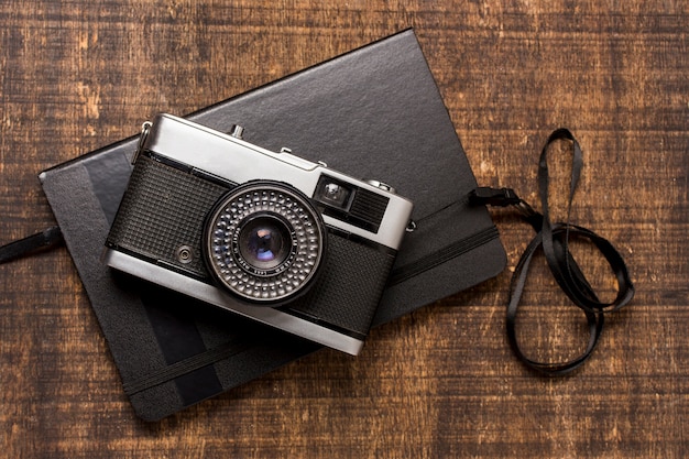 Kostenloses Foto eine altmodische kamera über dem geschlossenen tagebuch auf hölzernem schreibtisch
