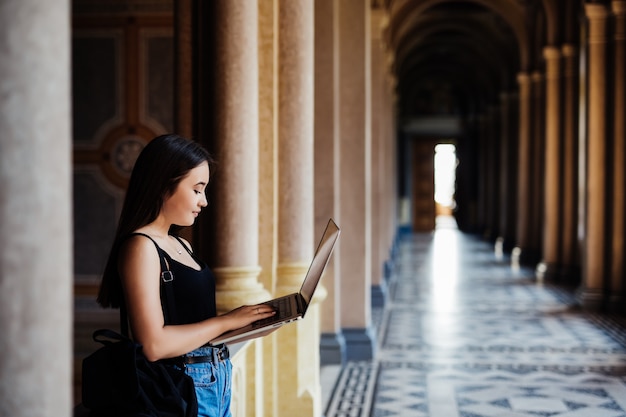 Eine asiatische Studentin, die auf dem Campus an ihrem Laptop arbeitet