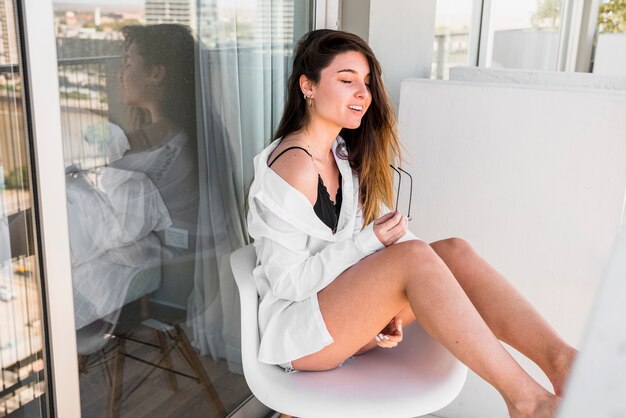 Eine attraktive junge Frau, die auf Stuhl im Balkon sitzt