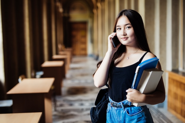 Eine Aufnahme eines asiatischen Studenten, der an der Universität am Telefon spricht