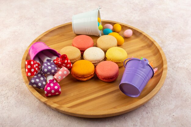Eine bunte französische Macarons der Draufsicht bilden rund und lecker auf dem rosa Schreibtischkuchen-Kekszuckersüß